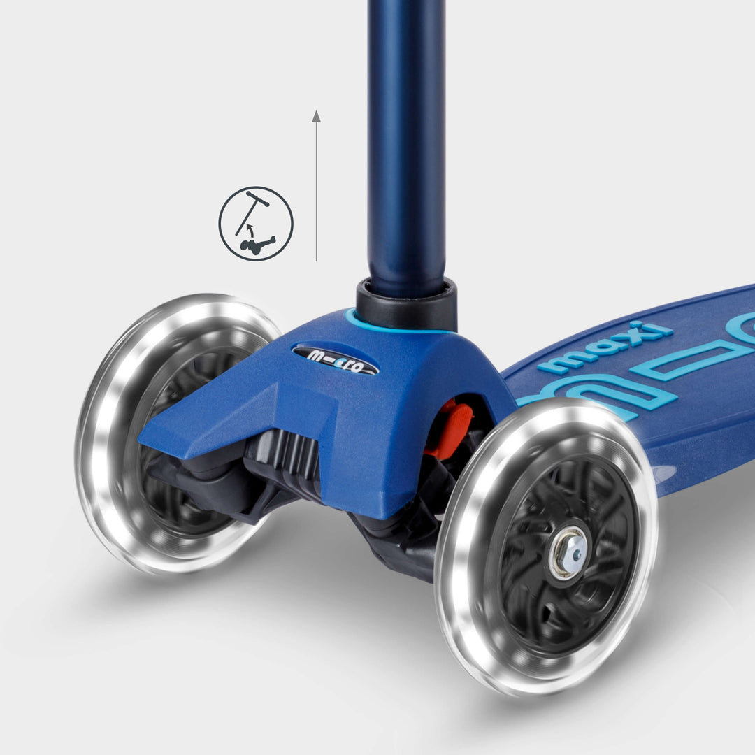 Close-up of the navy Maxi Micro Deluxe front wheels lit up, with a handlebar height-adjust icon