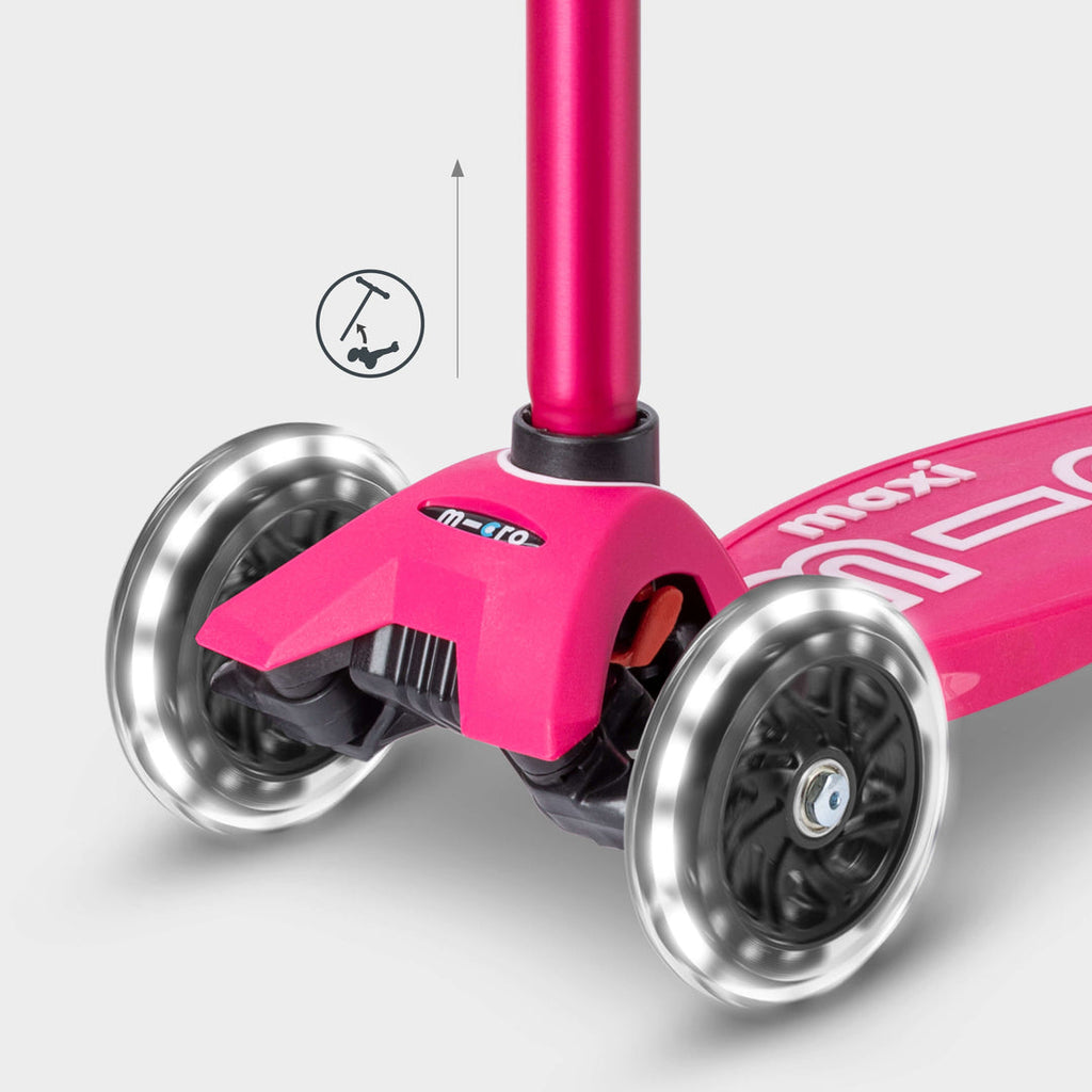 Close-up of the pink Maxi Micro Deluxe front wheels lit up, with a handlebar height-adjust icon