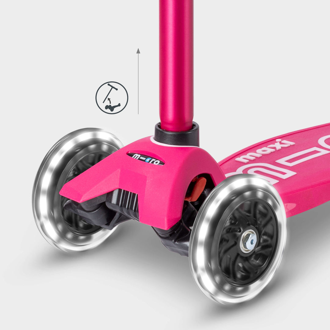 Close-up of the pink Maxi Micro Deluxe front wheels lit up, with a handlebar height-adjust icon