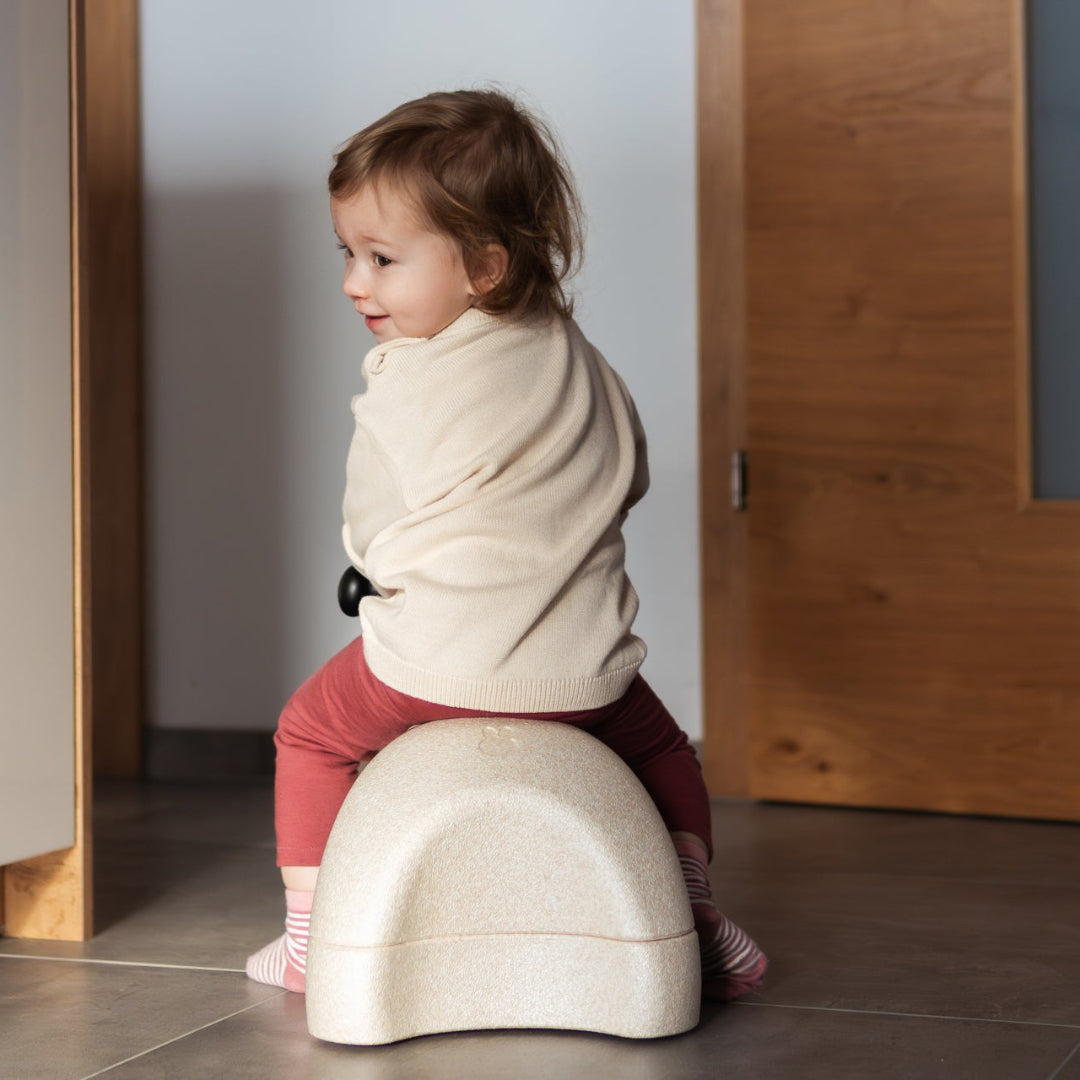 Child sitting on a miffy my first ride on in a kitchen