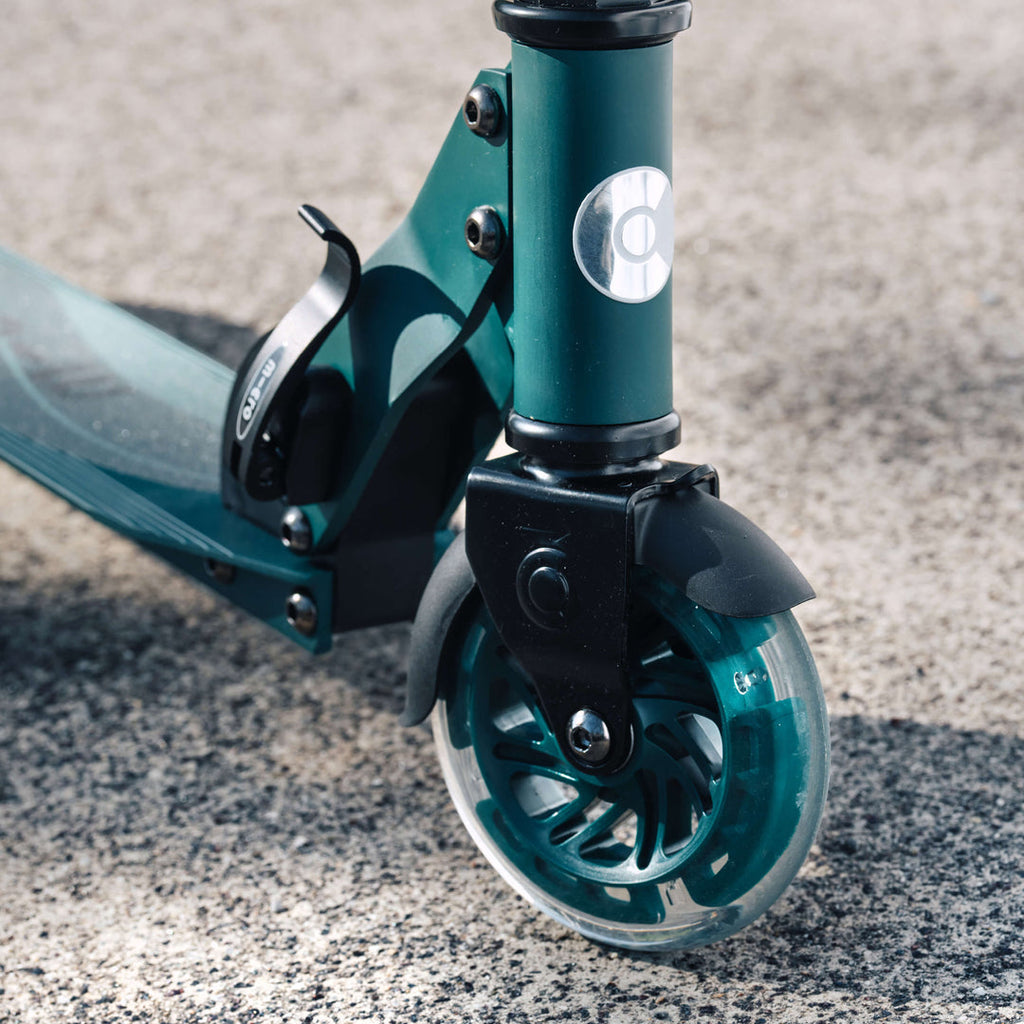 Close-up of the lit front wheel on the green Micro Recycled Sprite scooter on gravel
