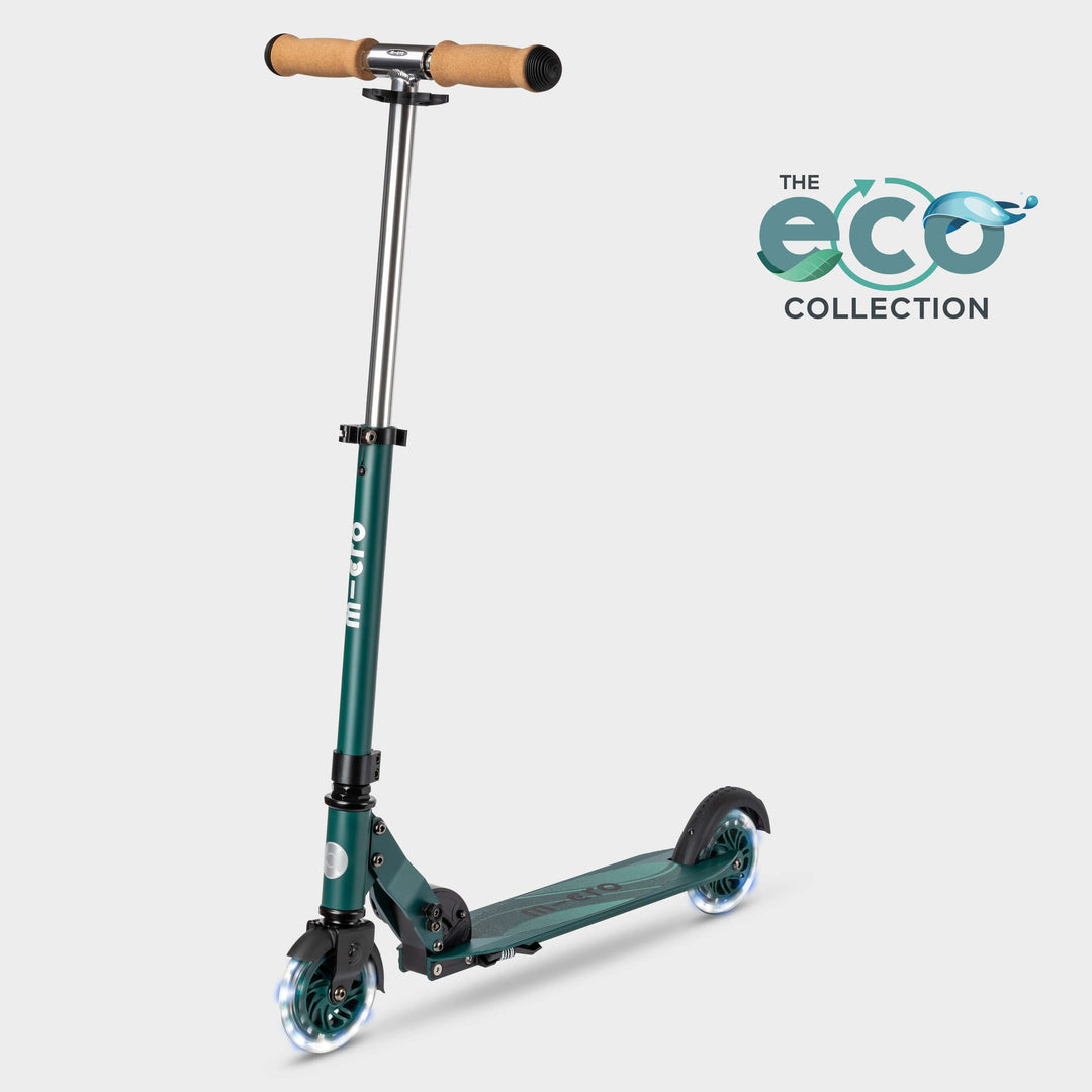 Micro Sprite LED two-wheel scooter in dark green with cork handlebar grips and light-up wheels, with the Eco Collection logo
