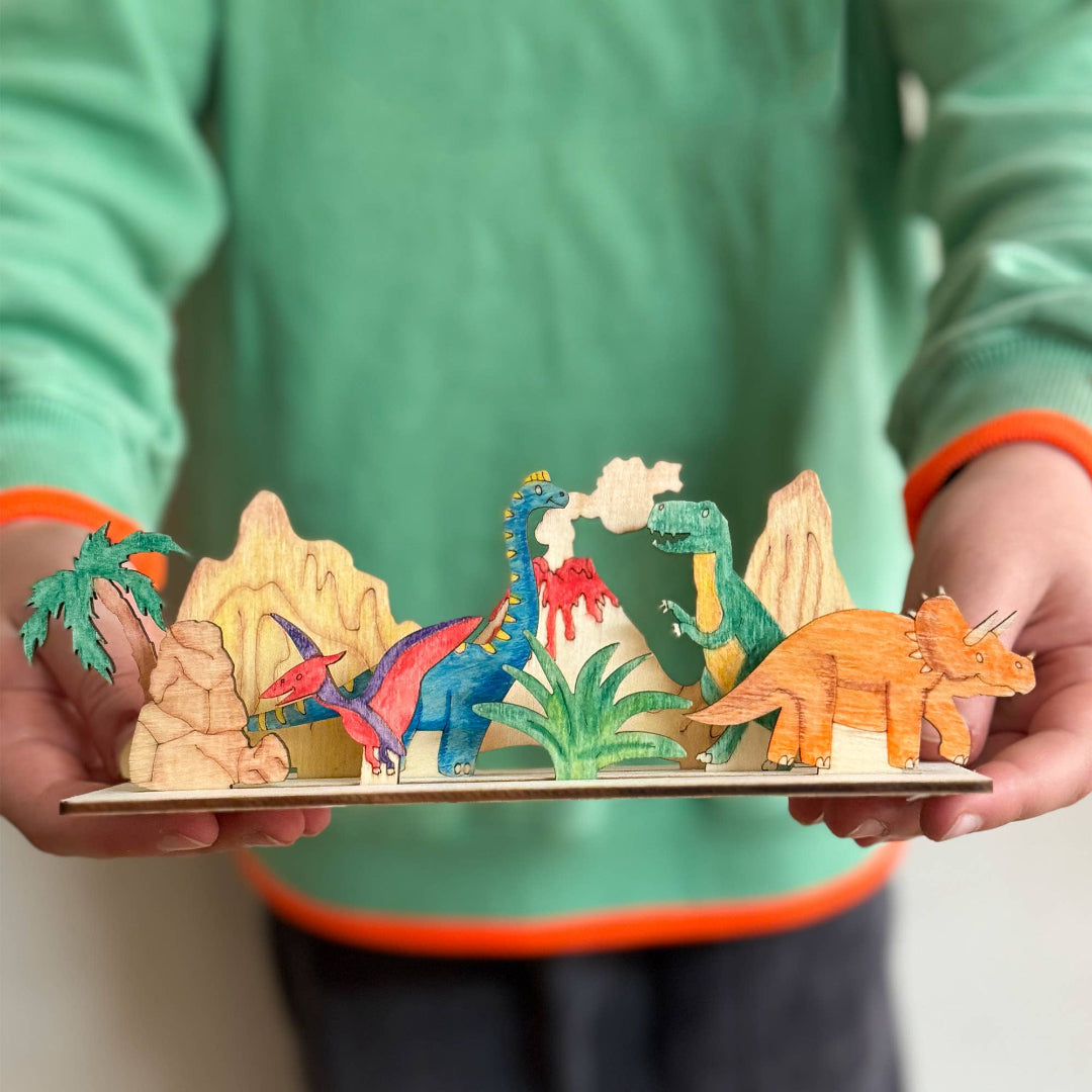 Colorful dinosaur toy set on a stand held by a person wearing a green shirt.