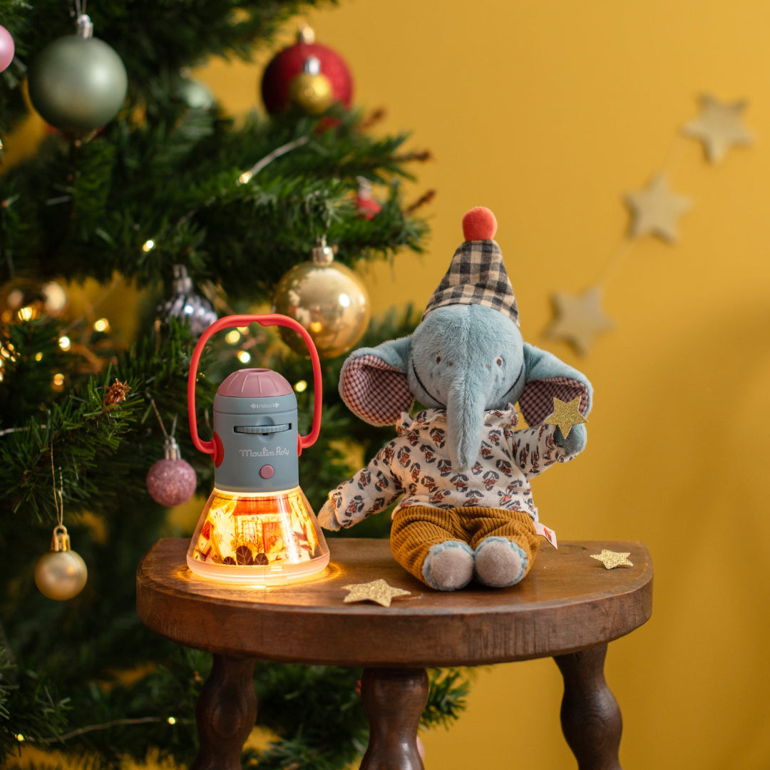 elephant soft toy sat on stool by christmas tree and toy lamp