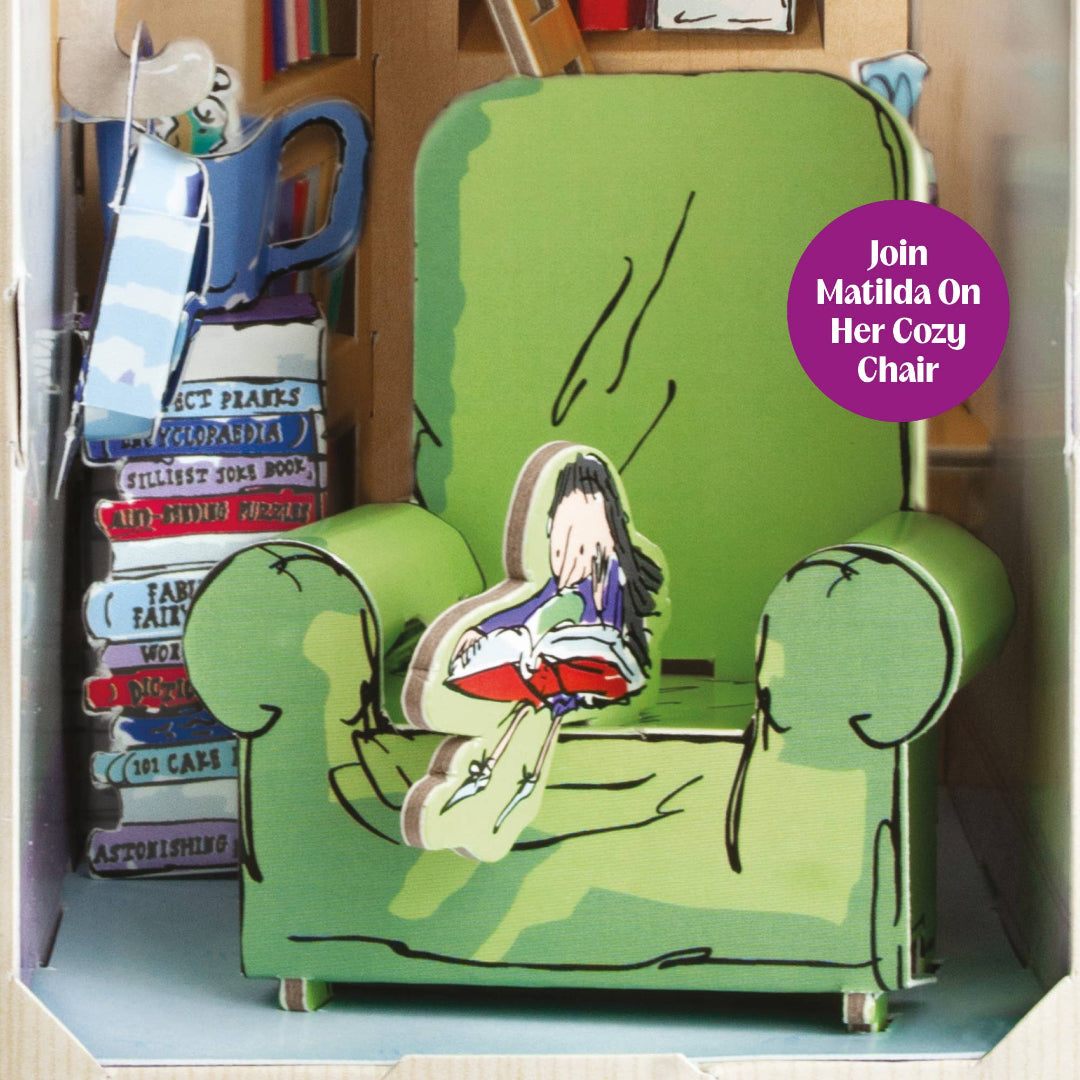 Green chair with a cutout of a girl reading a book, surrounded by books, in a display case.