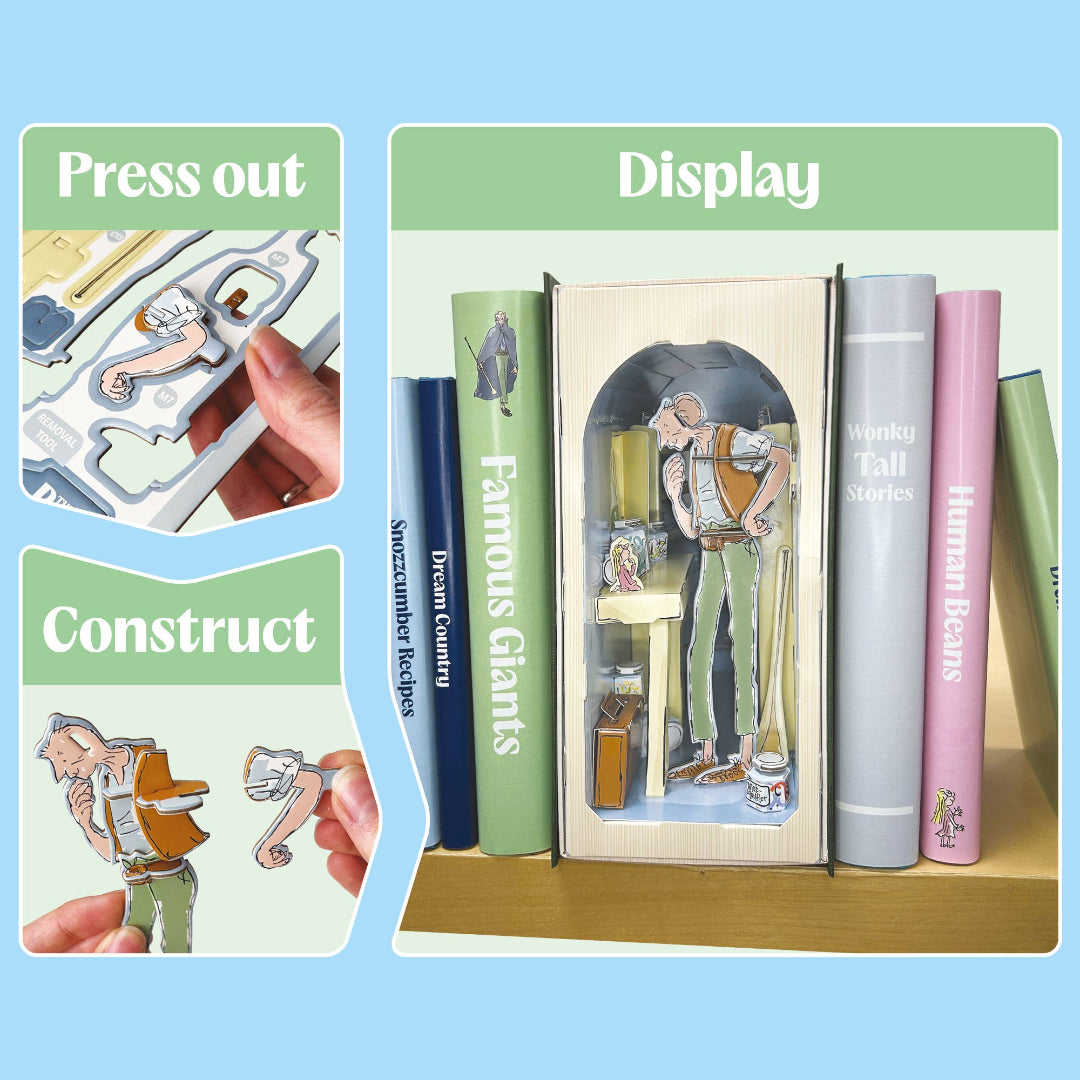 A children's book-themed display set featuring illustrated book spines and a central book with a window showing a tiny worker figure. The image includes inset panels labeled 'Press out' and 'Construct' showing hands assembling paper cutout pieces.