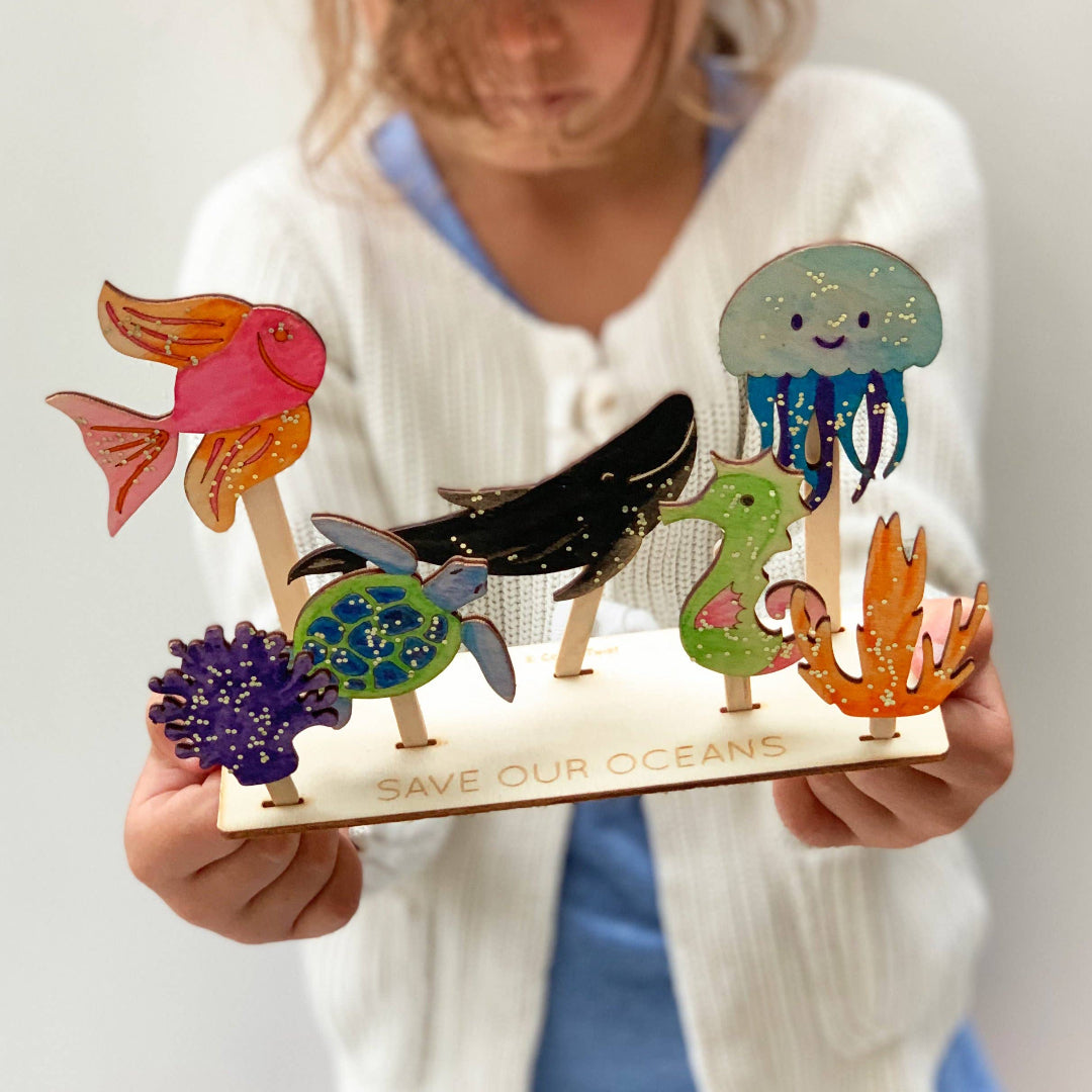 Person holding a set of colorful ocean-themed figurines with 'Save Our Oceans' message.
