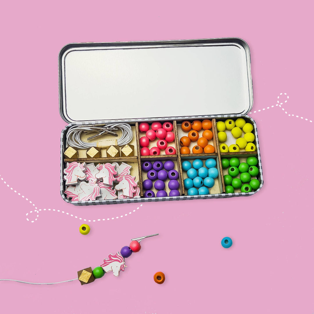Colorful bead set in an open tin on a pink background