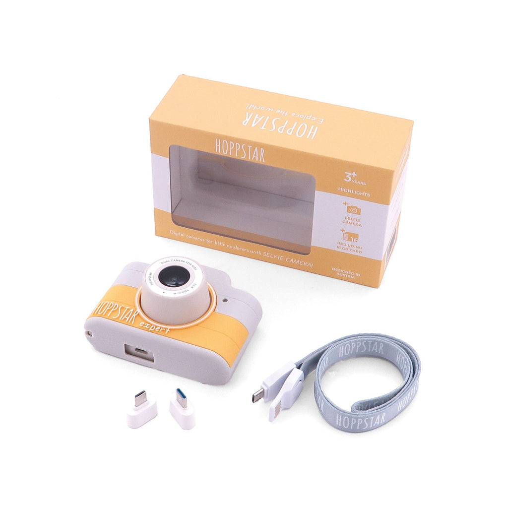 Digital camera with strap, earbuds, and packaging on a white background