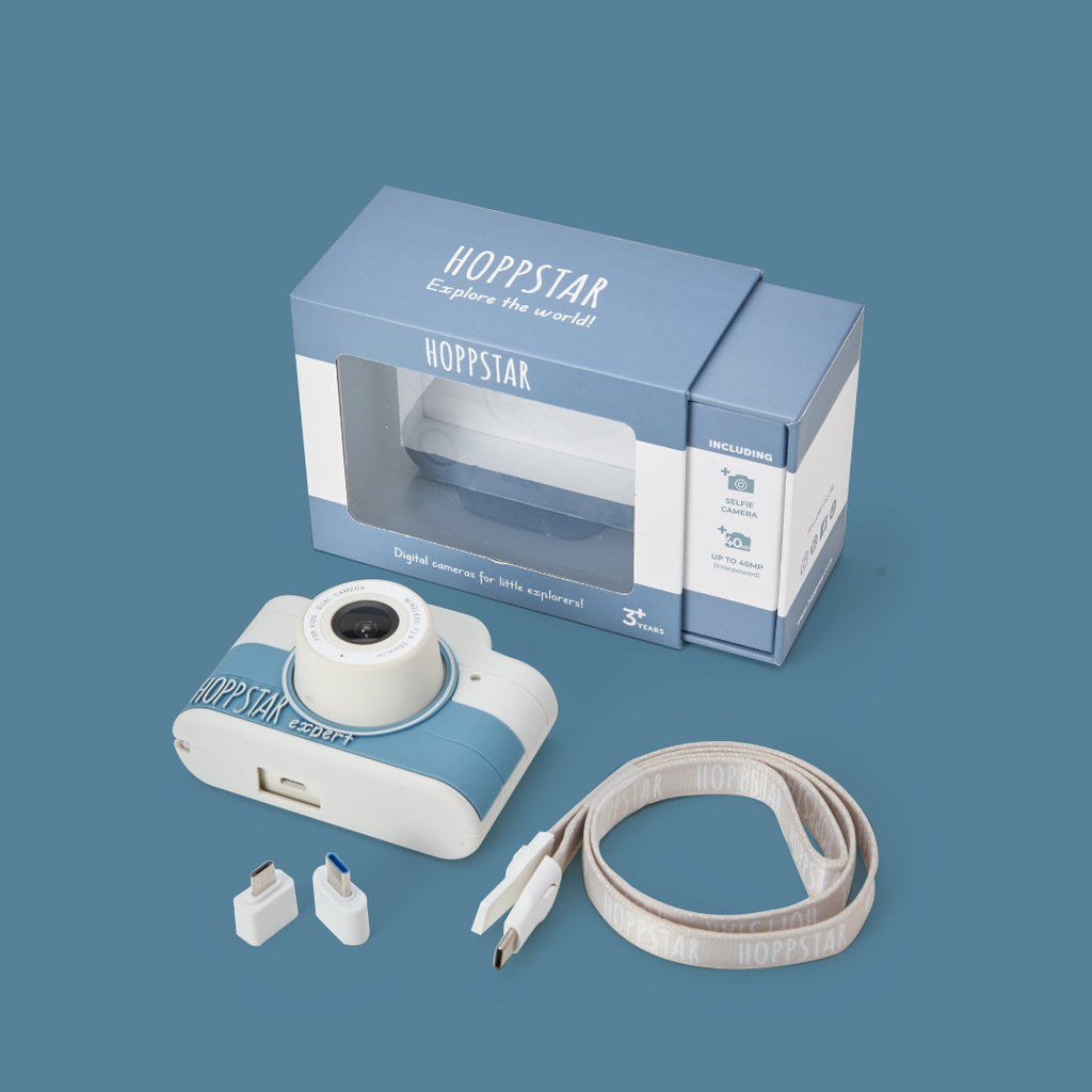 Hoppstar digital camera with packaging, strap, and accessories on a blue background