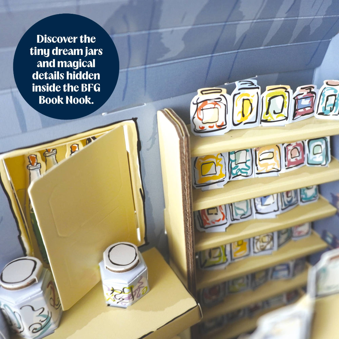 A close-up of a miniature book nook with cardboard shelves and small illustrated jars, plus a dark blue circular text badge that reads, 'Discover the tiny dream jars and magical details hidden inside the BFG Book Nook.'.