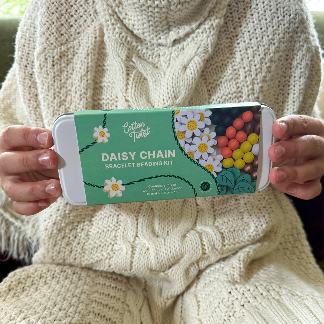 Person holding a 'Cotton Twist Daisy Chain Bracelet Beading Kit' packaging