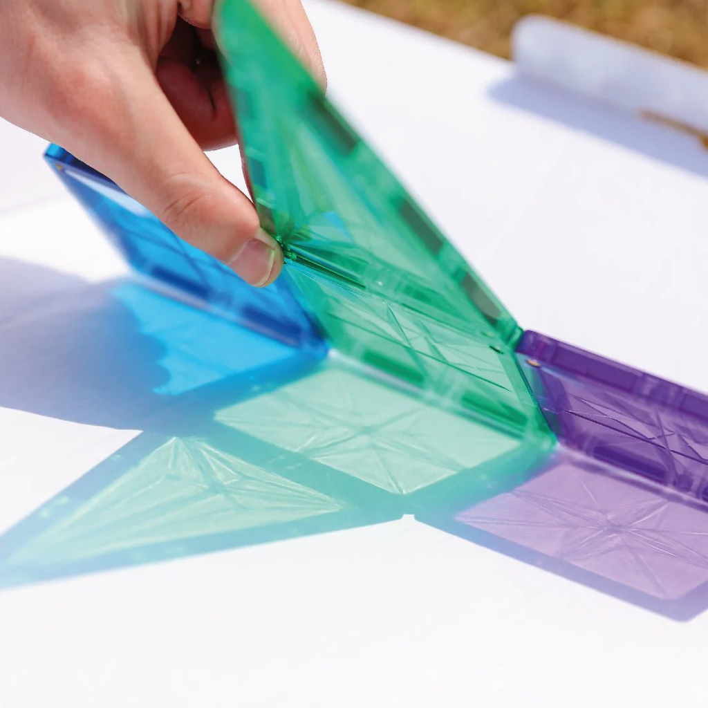 Colorful plastic templates on a white surface with a hand holding one of them.