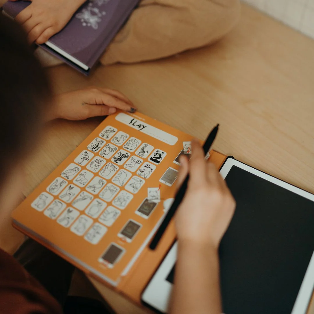 Person using a book with character cards and a pen on a wooden surface