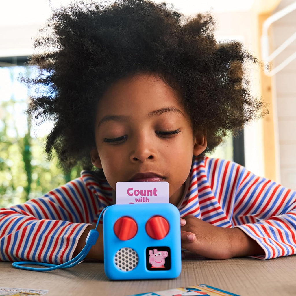 Child playing with a Yoto Player educational toy, Peppa Pig, on a table.