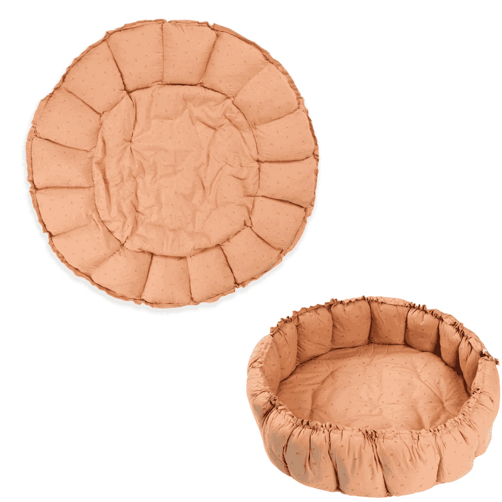 Round, cushioned pet bed in a peach color on a white background