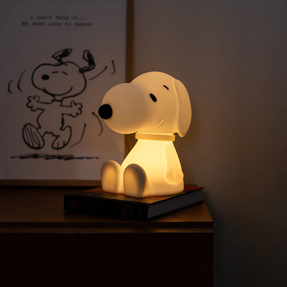 Snoopy lamp on a wooden surface with a small drawing of Snoopy in the background.