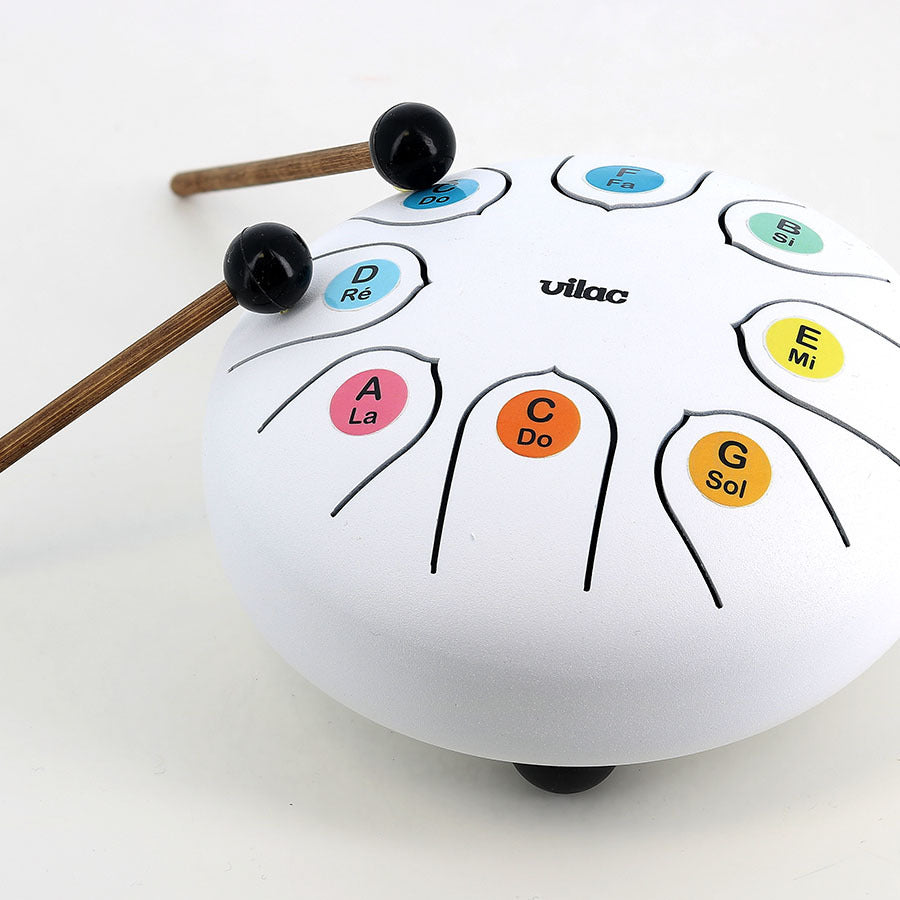 White tongue drum with musical notation and two drumsticks on a white background