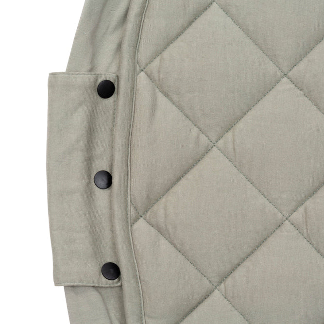 Quilted green fabric play mat with button details on a white background