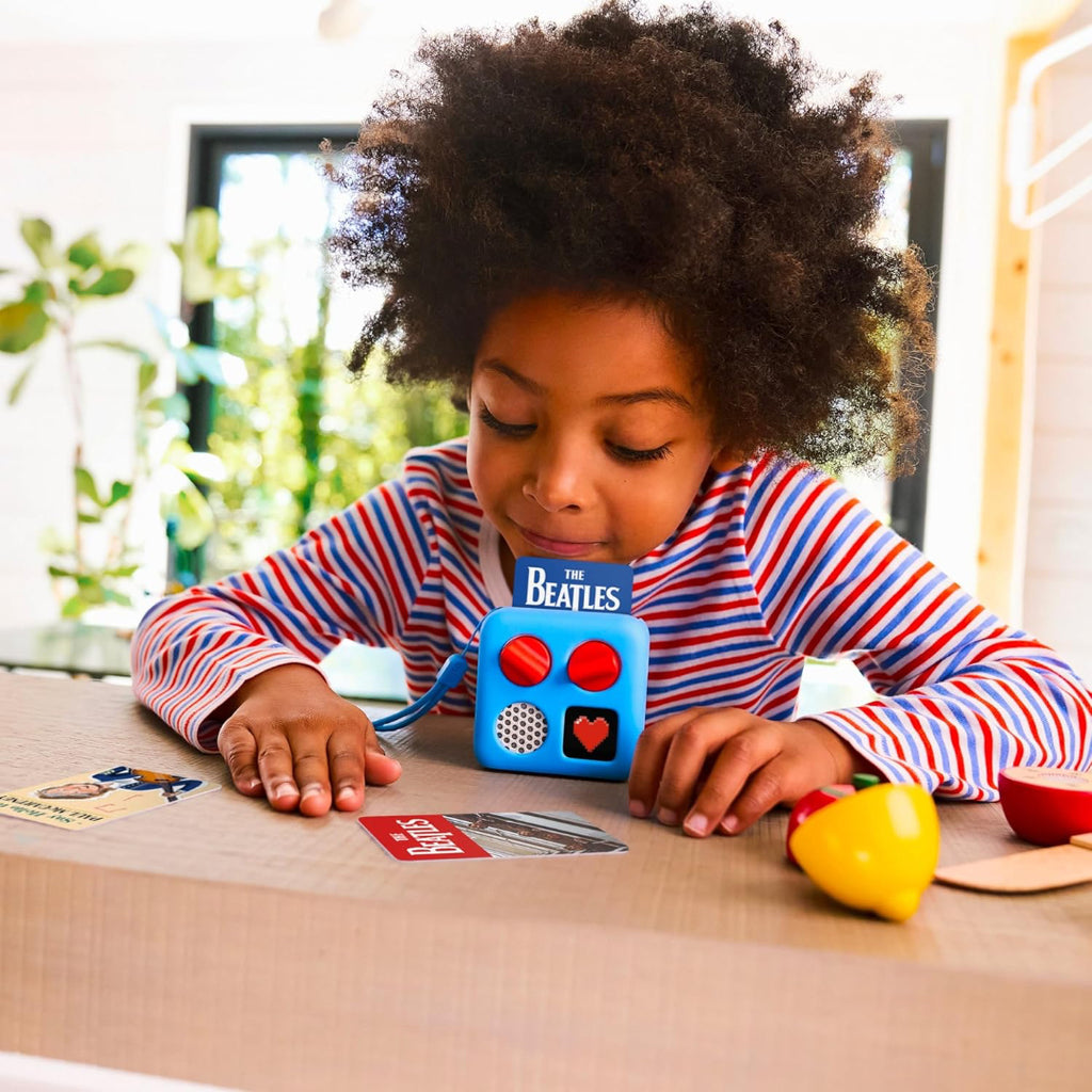 Child playing with Yoto with The Beatles card on a table.