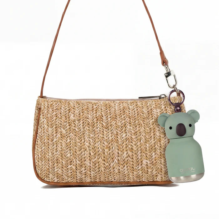 Woven handbag with a koala keychain on a white background