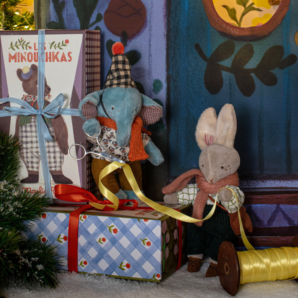 Toy elephant and rabbit with wrapped presents against a colorful wall.